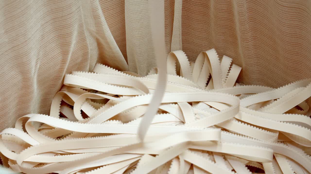 Close-up of tangled beige elastic straps on fabric backdrop