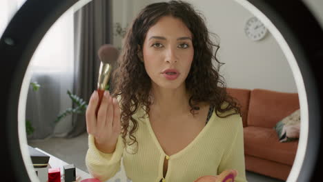 young woman filming makeup tutorial with ring light at home