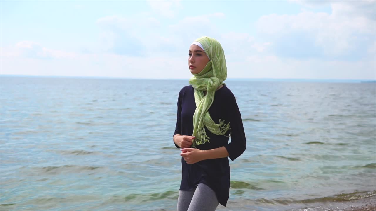 Woman in hijab running on the beach