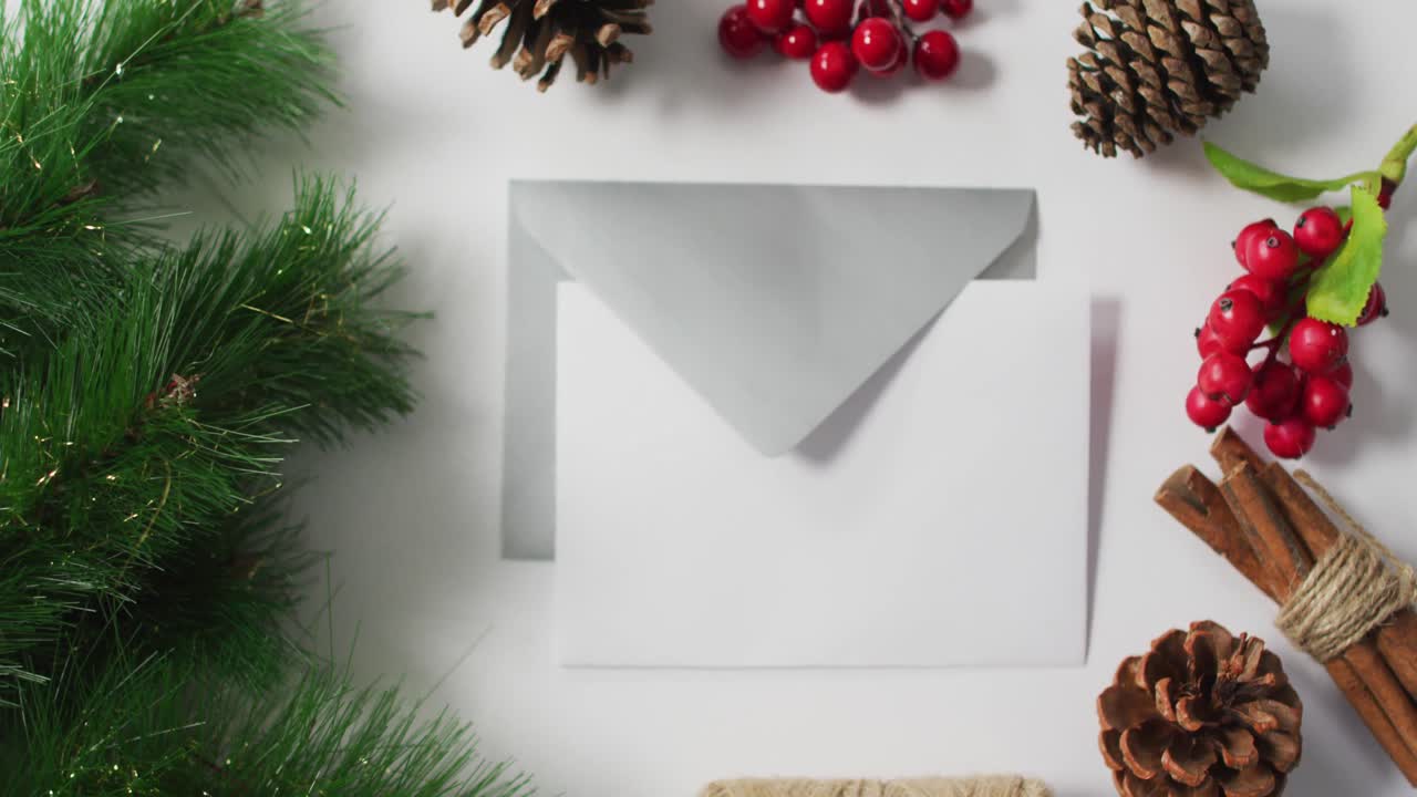 video de conos de pino de navidad, árboles y decoraciones de bayas rojas con sobres sobre fondo blanco