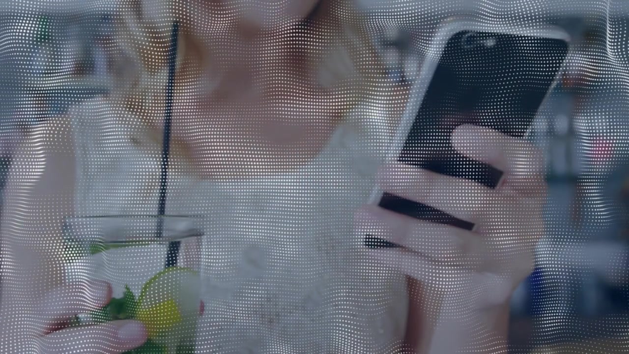 Woman in cafe holding smartphone and mint drink, thumb scrolling and reading, fading dotted overlay