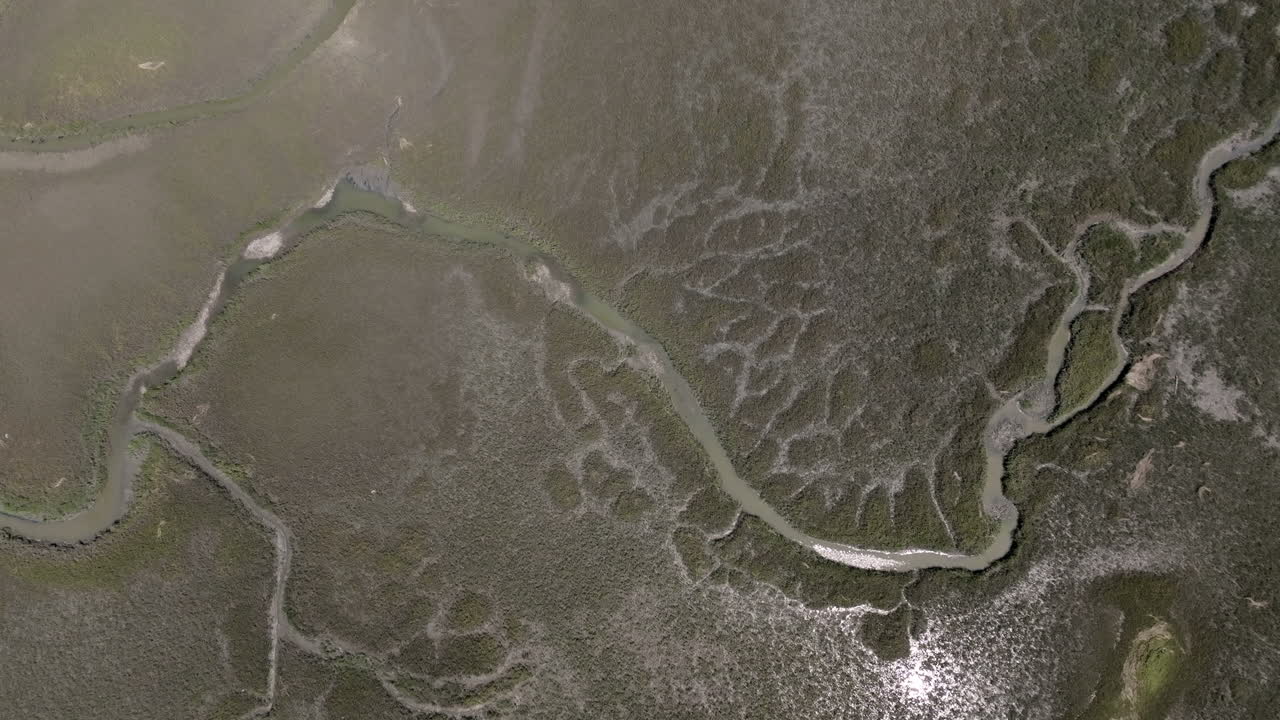 Aerial video looks straight down over Hilton Head’s salt marsh, revealing winding creeks and textured mudflats etched into the coastal plain