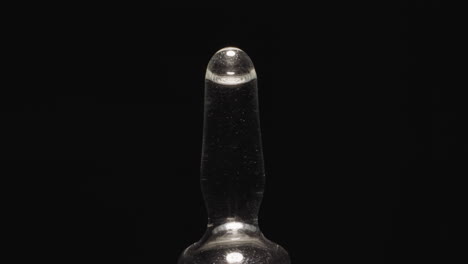 empty glass ampoule with long tip reflecting studio light