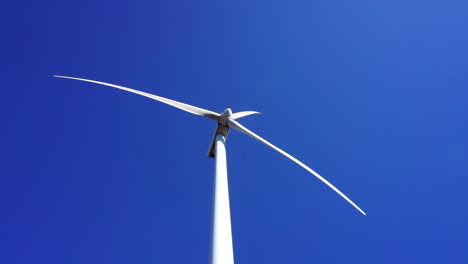 low angle view of a wind turbine spinning on a sunny, clear autumn day