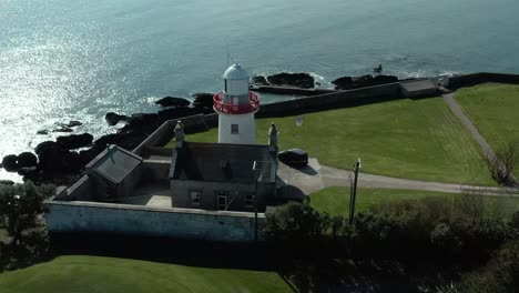 aerial orbit shot of lighthouse near sea coast in summer day