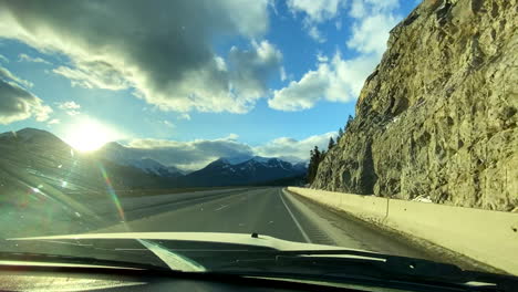 driving through the mountains in canada. looking through the front window, sun about to set.
