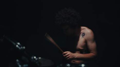 shirtless drummer in dark studio