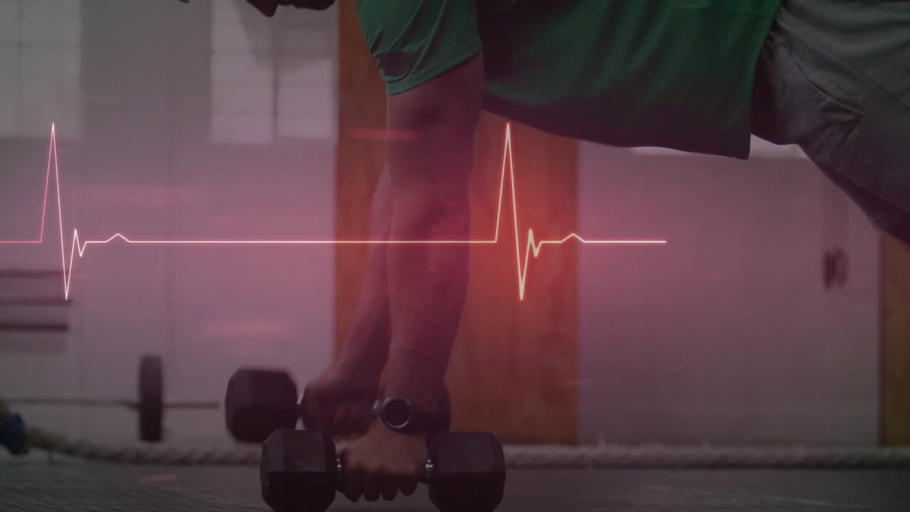 Muž dělá veslování s jednoručkou v pozici prkna s oporou na jedné paži pro zlepšení kondice, přičemž puls EKG je synchronizován s opakováními.