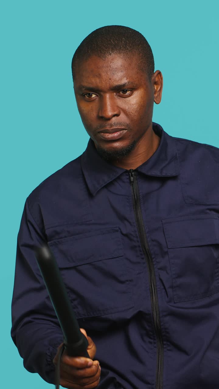 Uomo afroamericano serio che tiene una bacchetta in studio