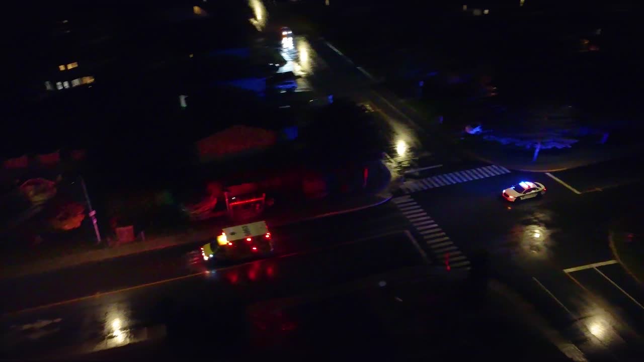 emergencia en una noche oscura de la ciudad, policía y ambulancia conduciendo por las calles, área suburbana, noche, cruzando una pequeña intersección