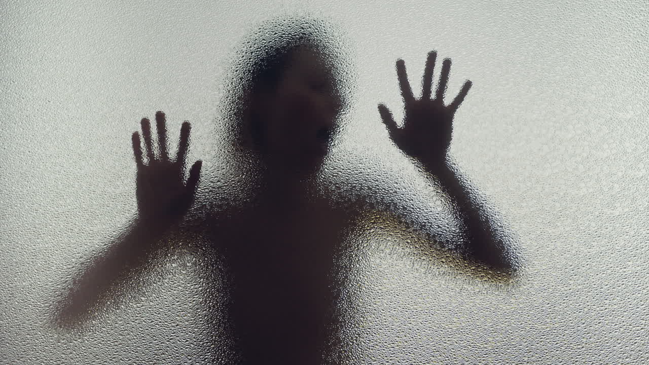A female silhouette behind the frosted glass moves slowly and screems
