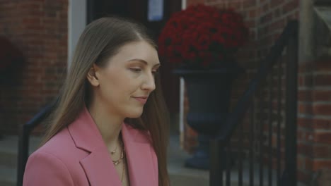 joven inteligente en un blazer rosa con una mirada alegre y una sonrisa en la calle durante el día