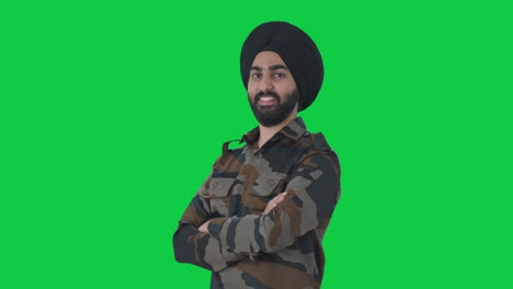 retrato de un feliz sikh hombre del ejército indio de pie con las manos cruzadas pantalla verde