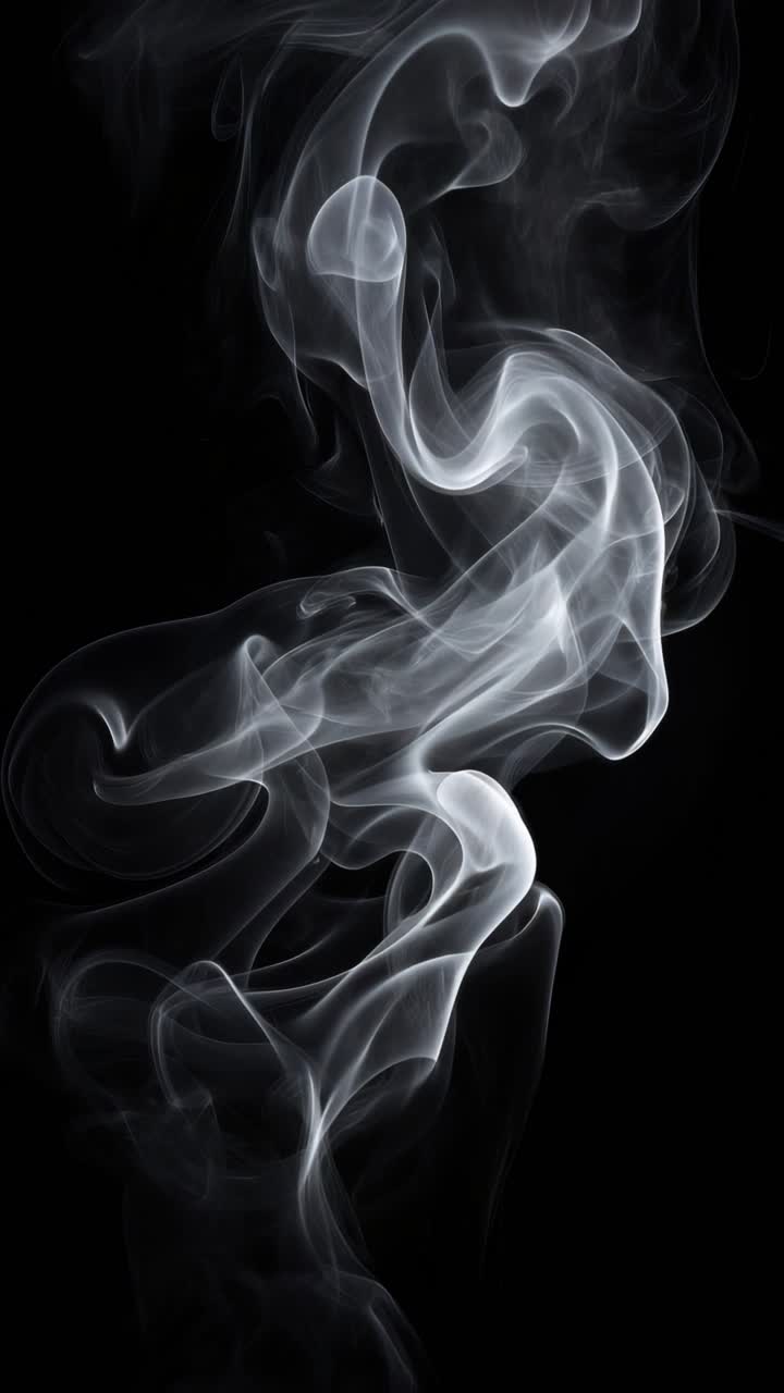 Il fumo etereo turbina su uno sfondo nero, catturato in un primo piano, ad angolo verticale