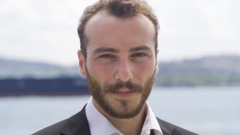 un hombre de negocios sonriente mirando a la cámara junto al mar.