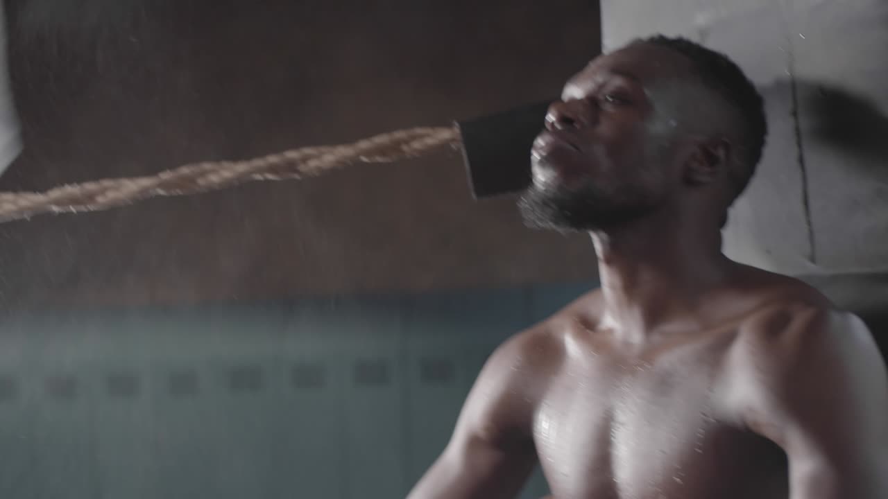 boxeador afroamericano descansando y bebiendo en la esquina del ring durante el partido