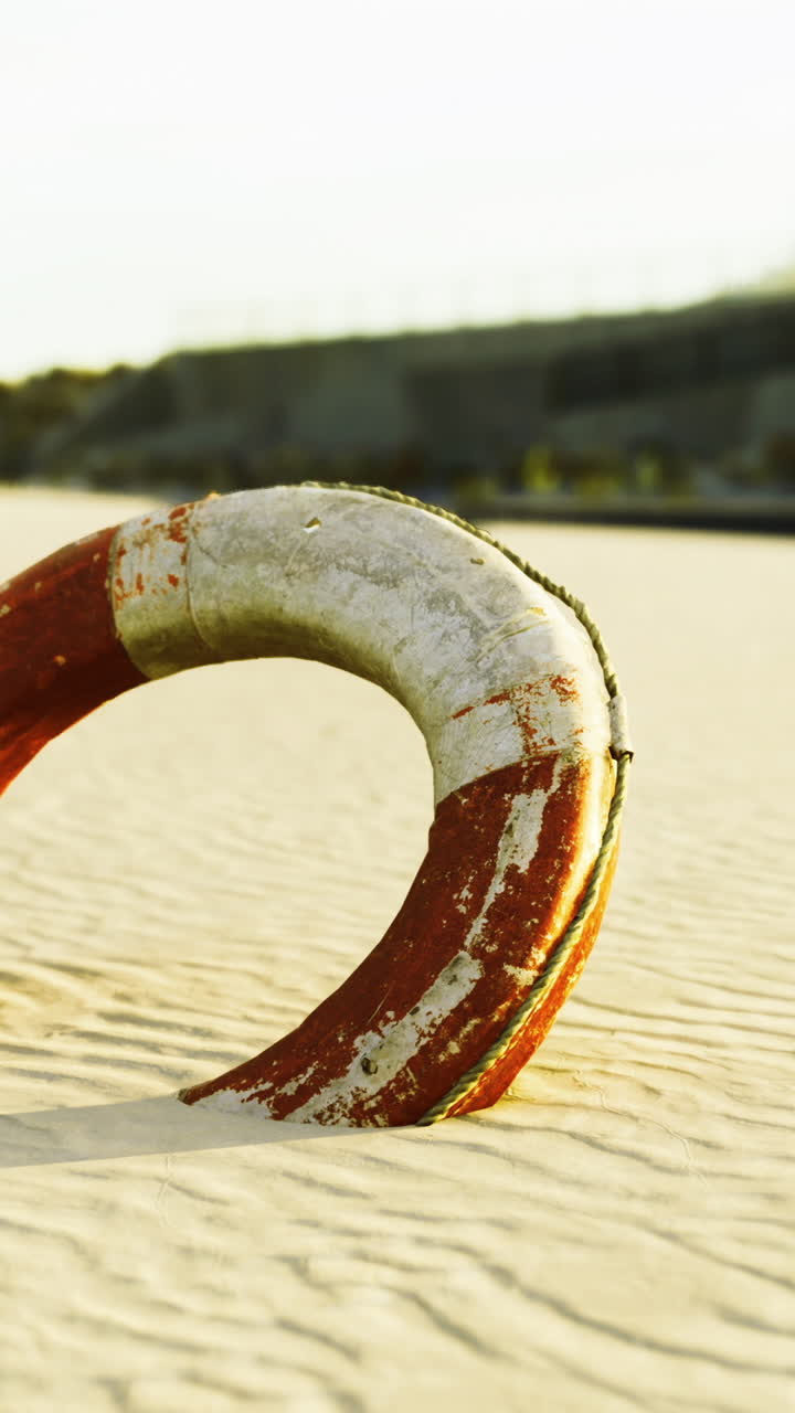 Salvagente su spiaggia sabbiosa illuminato dalla luce dorata nelle prime ore del mattino