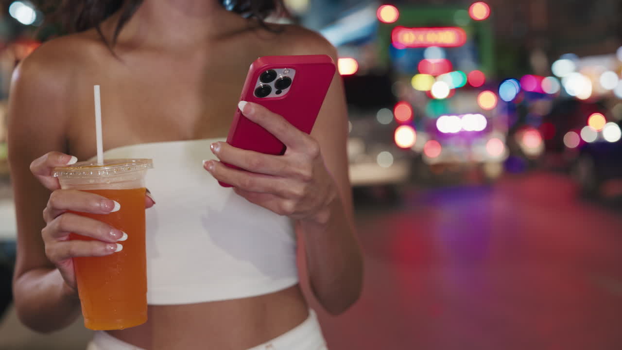 Woman enjoying street food and using mobile phone at night market
