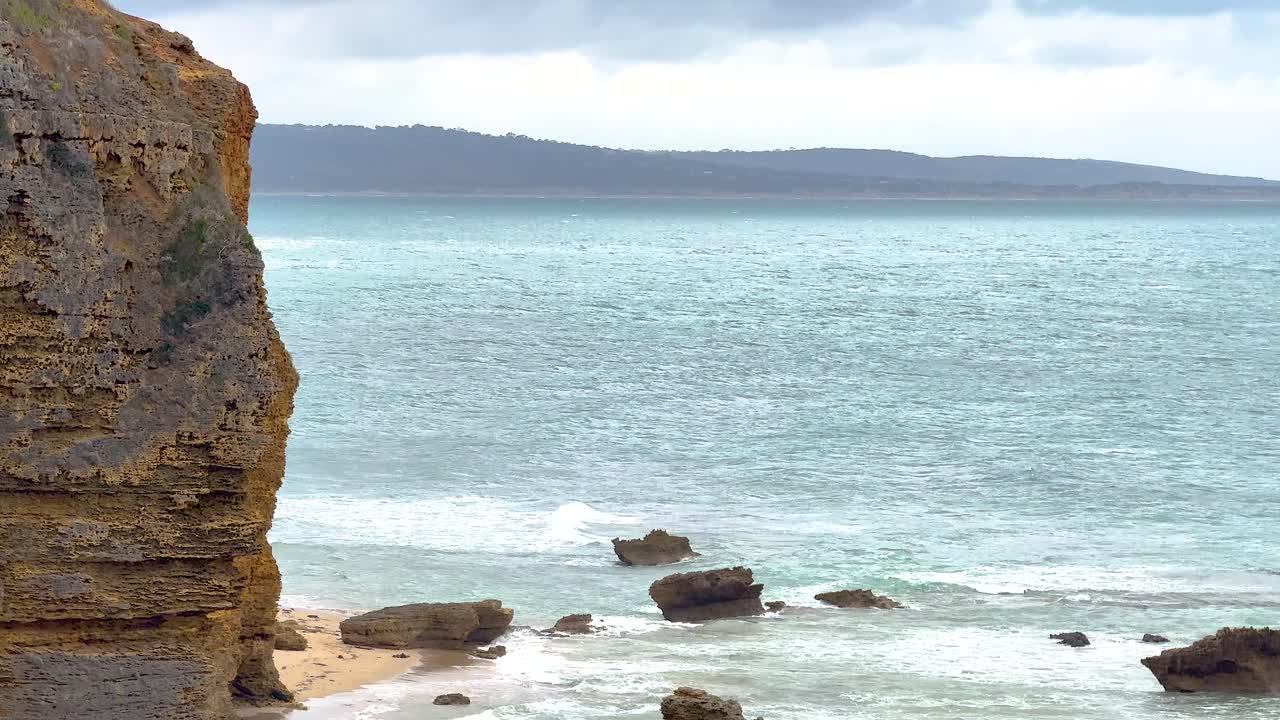 A tranquil scene of ocean waves gently hitting rocky cliffs under soft daylight at Port Campbell, Australia