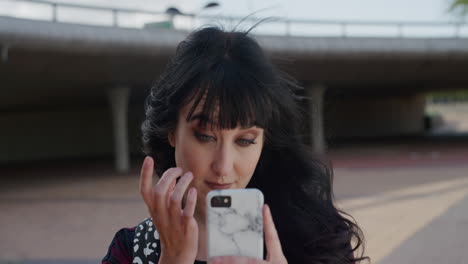 retrato de una hermosa mujer joven comprobando el maquillaje usando un teléfono inteligente preparándose para una entrevista de reunión mujer independiente con anillo en la nariz trasfondo urbano