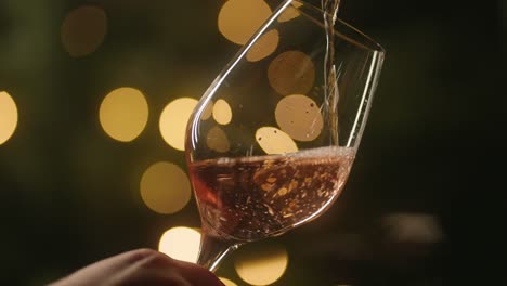 Waiter-Pouring-A-Glass-Of-Cold-Rose-Wine,-Xmas-tree-background