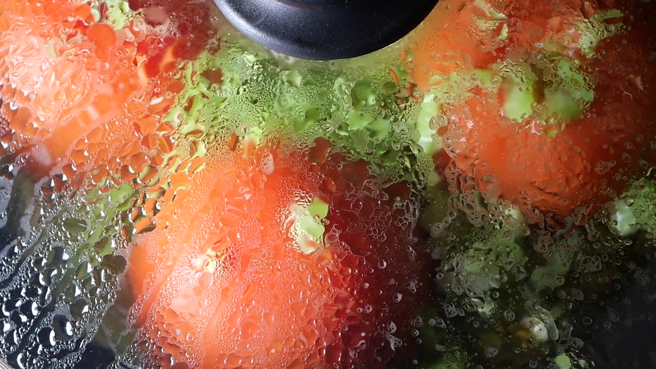 Pomodori freschi che cuociono in una padella sotto un coperchio di vetro