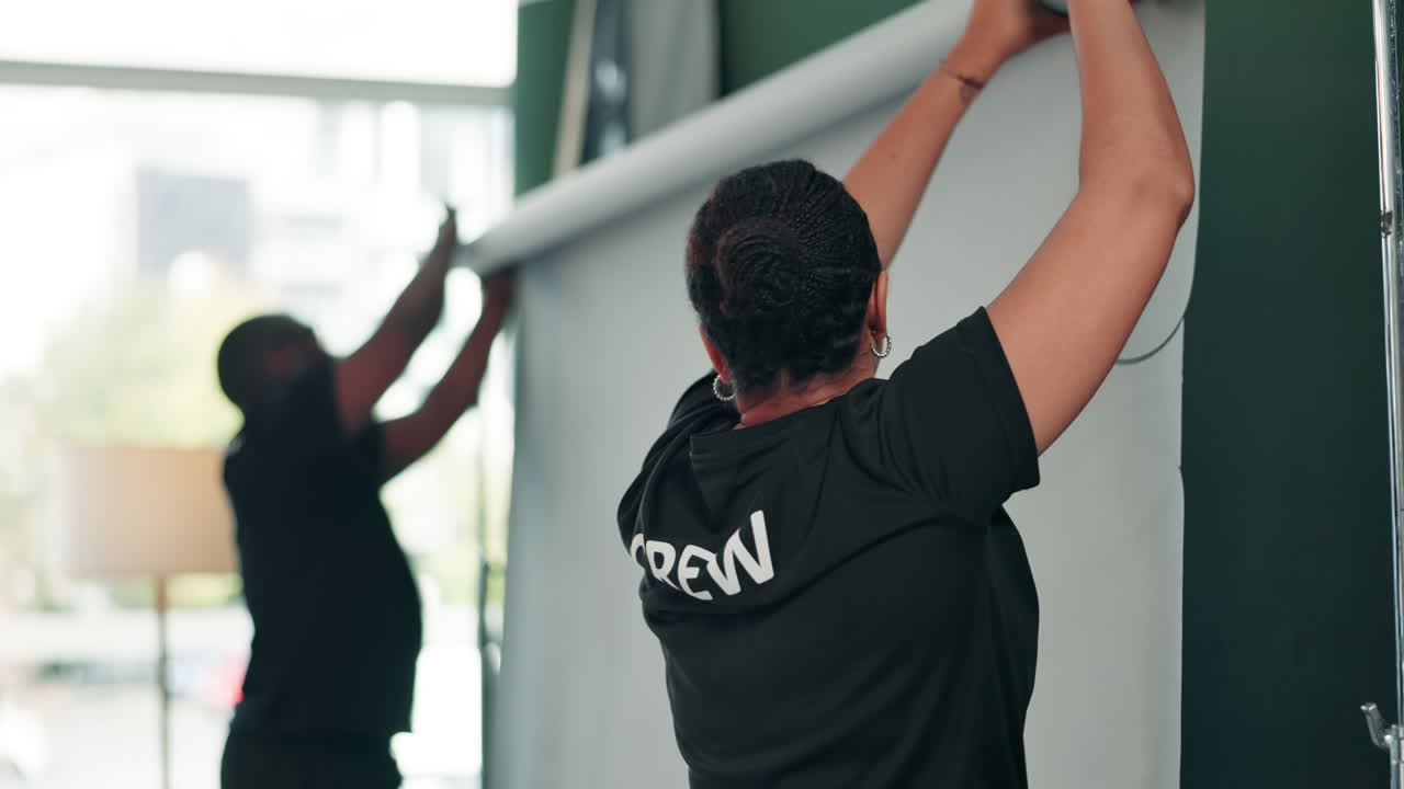 Film crew setting up backdrop in studio