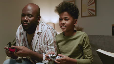 Black-man-and-boy-playing-video-games-at-night