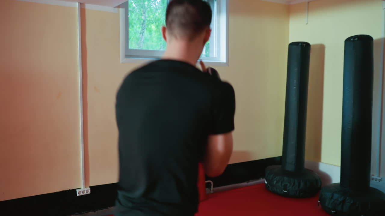 Wrestlers engaged in sparring inside gym, one delivering punch while other defends with gloves, showcasing strength, focus, combat skill, endurance, determination during martial arts training