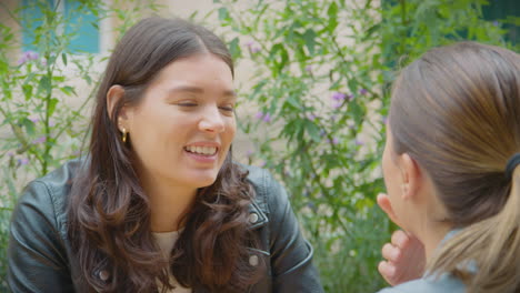 Happy-Same-Sex-Female-Couple-Meeting-And-Sitting-Outdoors-At-Coffee-Shop-Together