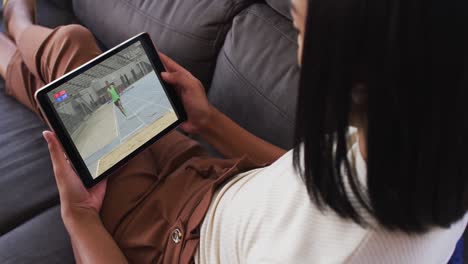 composite of woman on couch at home watching athletics long jump event on tablet