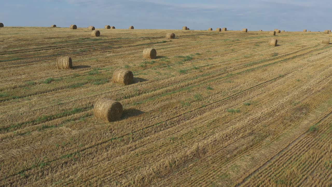 vuelo lateral sobre balas de heno bajo cielo azul imágenes de drones 4k