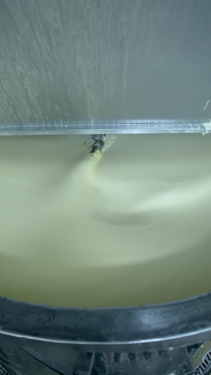 Industrial equipment for making butter. Modern container mixing butter at milk factory. Creamy dairy product in a tank.. Vertical video