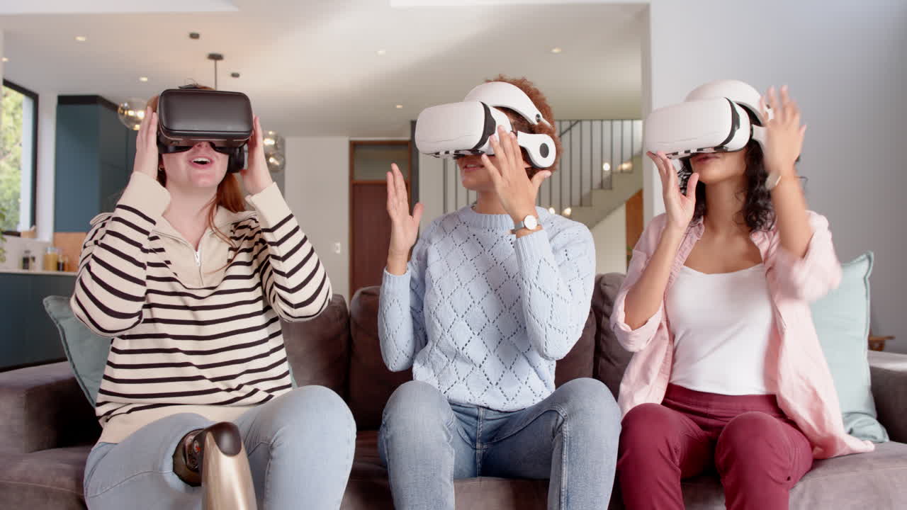 Using VR headsets, diverse female friends enjoying virtual reality experience on couch