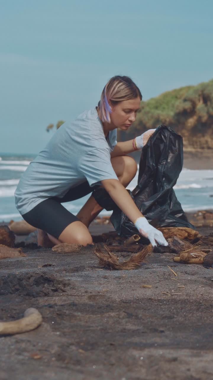 Young caucasian woman volunteer removes garbage from beach to help nature