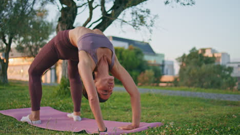 ejercicio de yoga de gimnasta flexible en una alfombra de goma en la naturaleza de verano. postura de puente de mujer