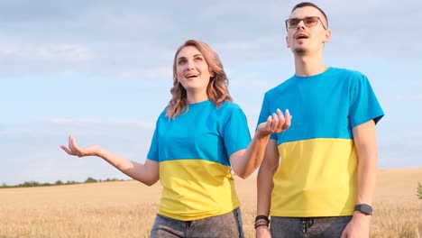a man and a woman are singing in the middle of a wheat field a man and a woman are singing in the middle of a wheat field concept of war in ukraine ukrainian family dressed in blue and yellow colors