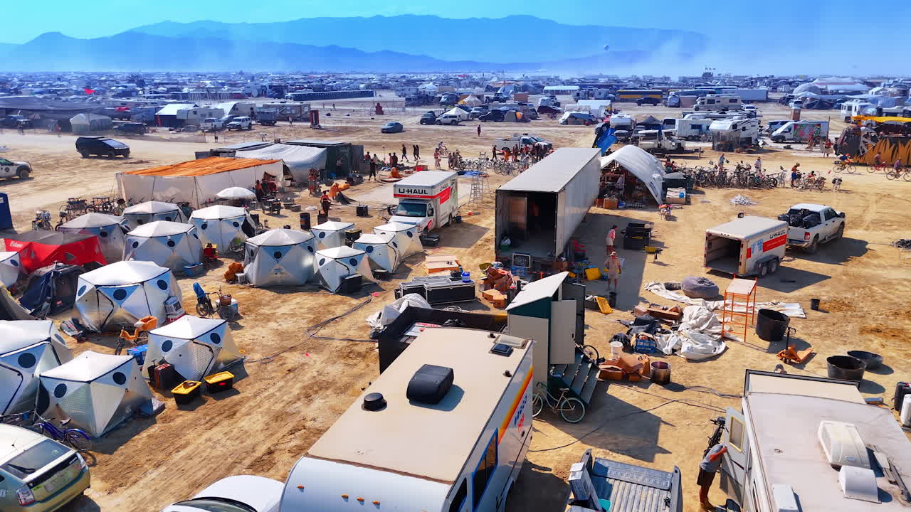 Nevada, USA, 25 August 2025: Aerial drone view of a busy Burning Man camp area filled with tents, vehicles, and people surrounded by the dusty desert landscape