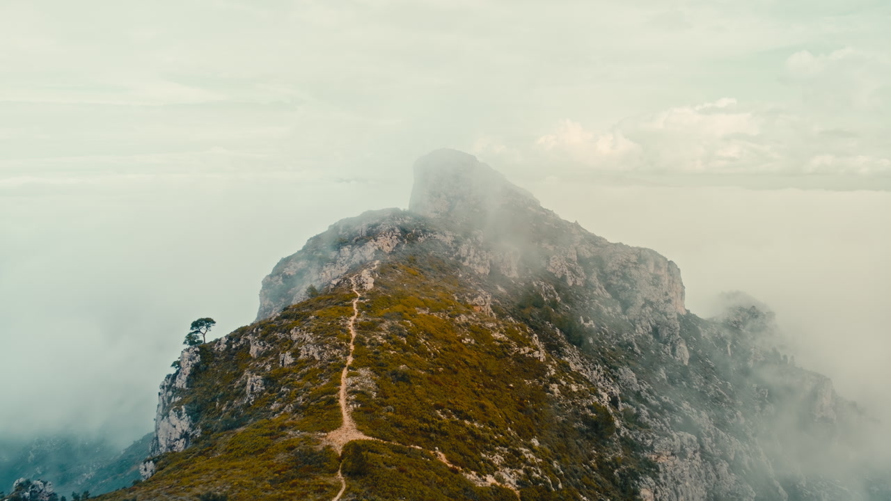 epic 4K aerial drone footage traveling over mountain path through low misty clouds. Moody atmospheric