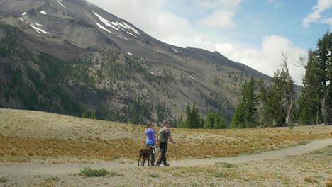 dos excursionistas y su perro caminan juntos