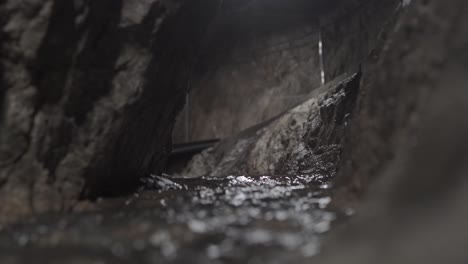 water flows through a creek in a cave while people walk by on a path