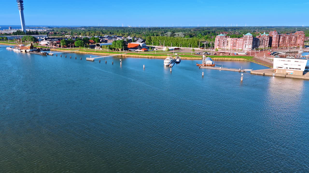 Flying over the calm waterscape of lake Markermeer with a picturesque shore. View on the boats, ships port and telecom tower of Lelystad, the Netherlands.