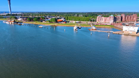 Flying over the calm waterscape of lake Markermeer with a picturesque shore. View on the boats, ships port and telecom tower of Lelystad, the Netherlands.