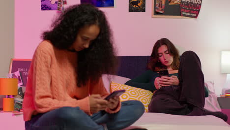 two teenage girls using smartphones in a bedroom