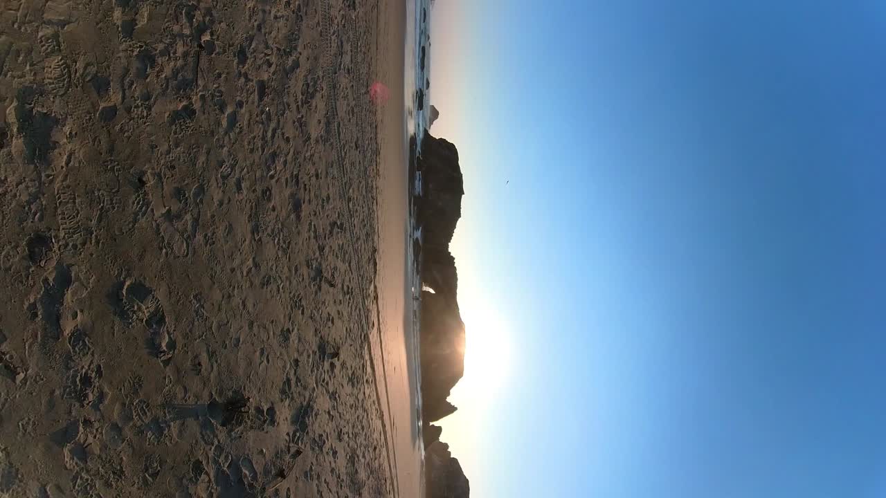 toma móvil de una cueva marina en la playa de bandon mientras se pone el sol.
