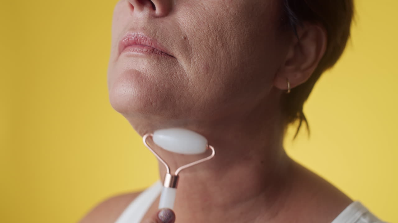Middle-aged Woman Smoothing Wrinkles on Face and Neck with Gua Sha