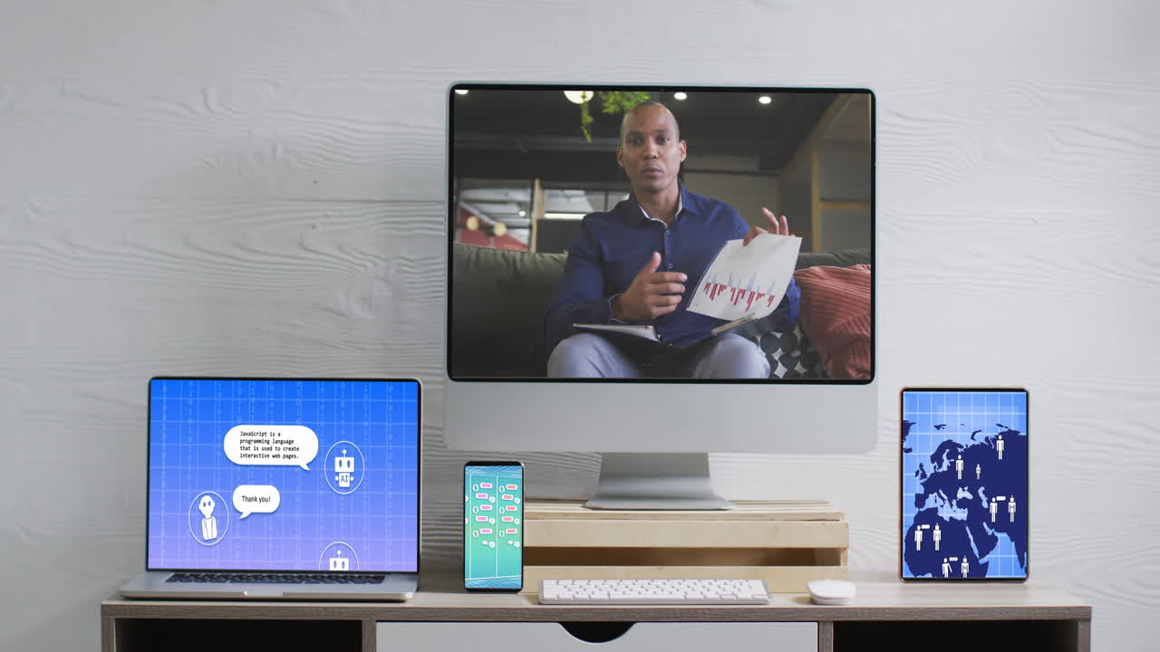 African american businessman on video call and electronic devices with data processing on screens