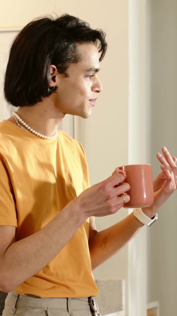 Video verticale: Uomo risponde a un prompt, tiene una tazza rosa e gesticola in cucina con uno smartwatch.