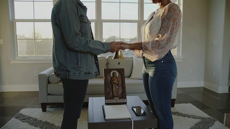 Couple Holding Hands Over Religious Icon and Bell in Living Room