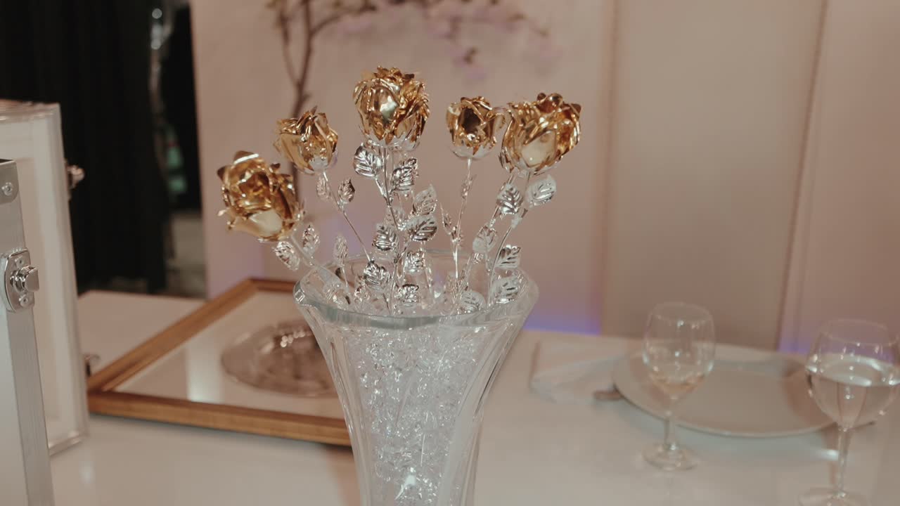 Metallic gold and silver rose decorations displayed in clear vase